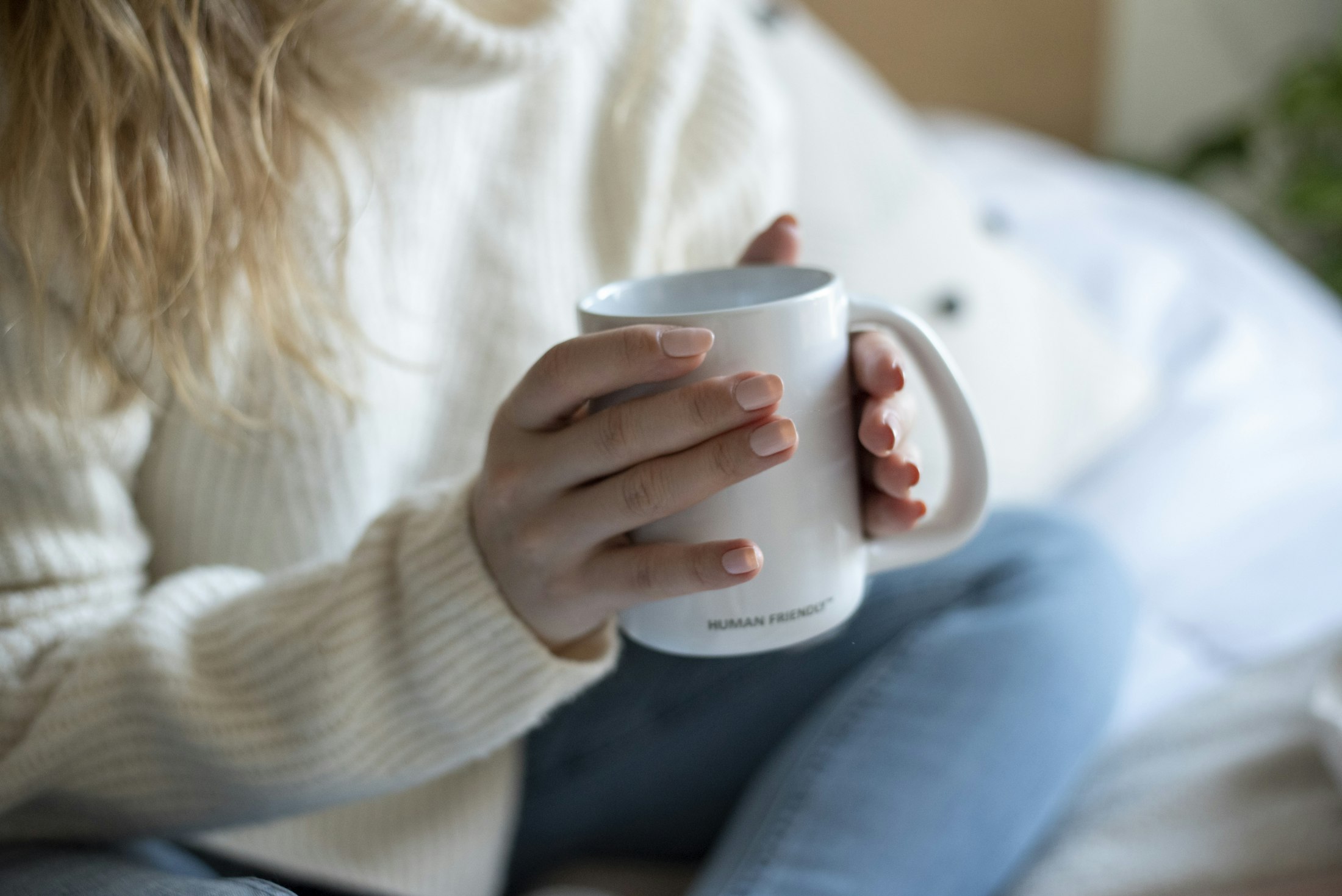 Mãos segurando uma caneca branca, com luz suave