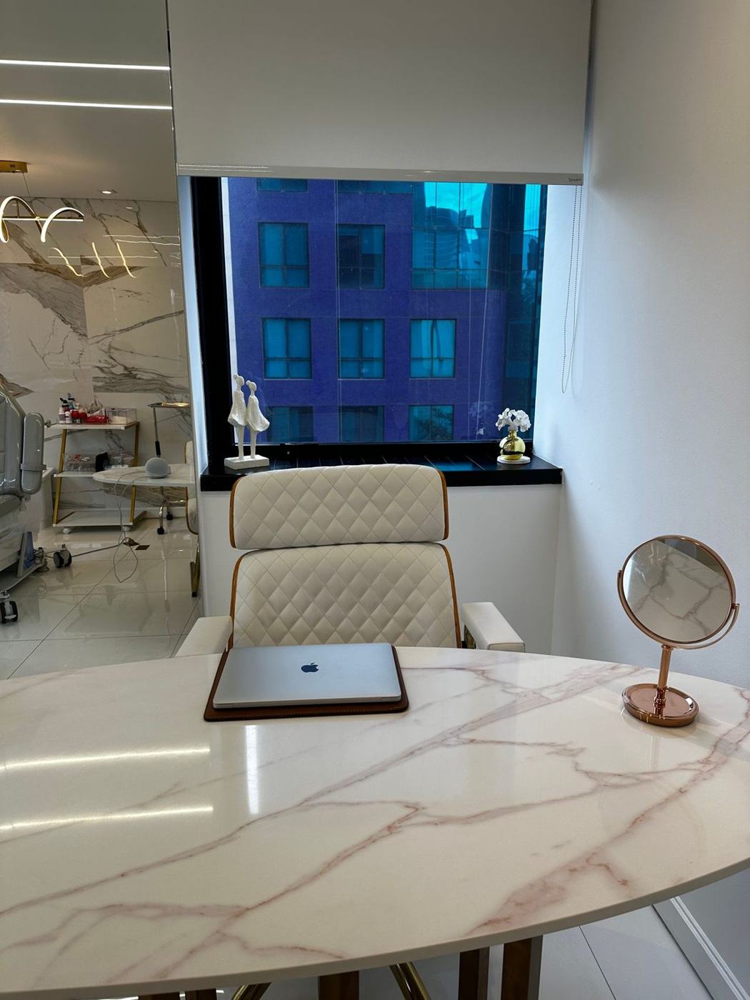 Sala de atendimento com mesa de mármore e janela para a rua