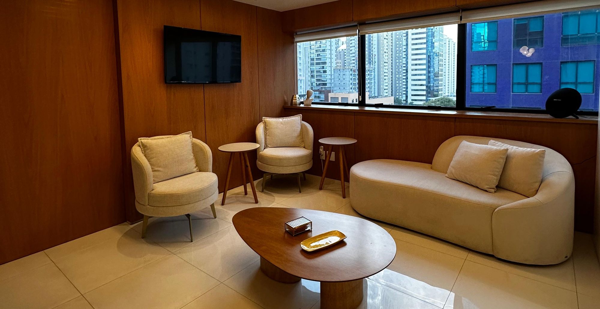 Sala de espera do consultório em Moema, com sofá, poltronas e painéis de madeira
