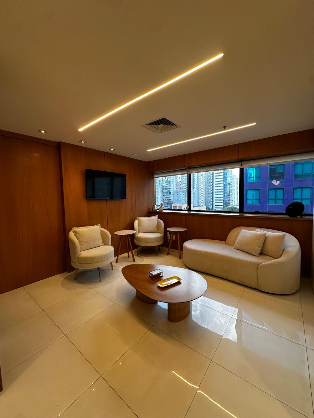 Sala de espera com sofá, poltronas e painéis de madeira